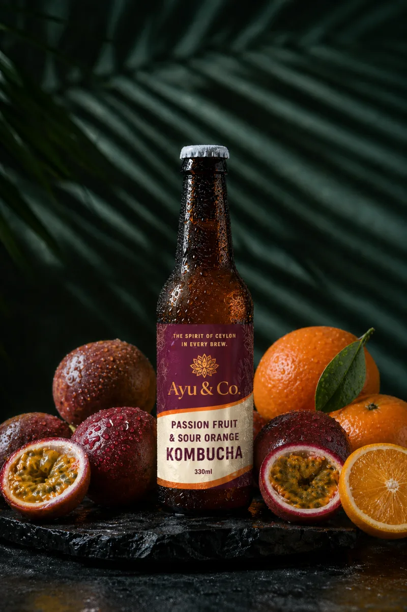 Ayu & Co. Passion Fruit & Sour Orange Kombucha bottle on a stone plate with whole and halved passion fruit and oranges
