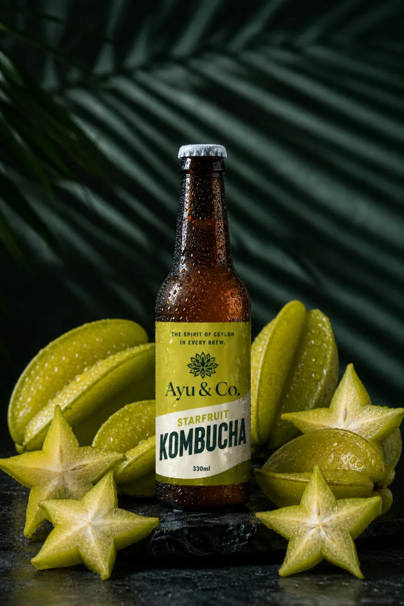 Ayu & Co. Starfruit Kombucha bottle surrounded by whole and sliced star-shaped Ceylon starfruit